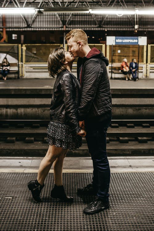 情侣站在火车站平台上接吻的照片 · 免费素材图片