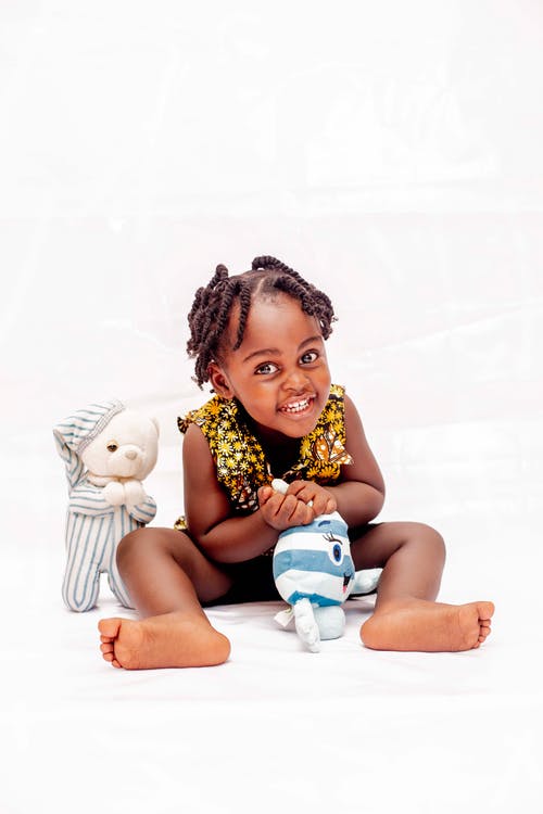 蹒跚学步的女孩微笑和抚摸玩具 · 免费素材图片