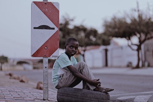 男孩坐在路标旁边的轮胎 · 免费素材图片