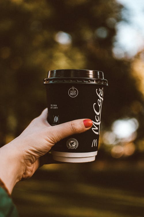 女人的手捧出一杯麦卡菲咖啡的选择性焦点照片 · 免费素材图片