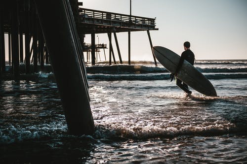 男子携带冲浪板 · 免费素材图片