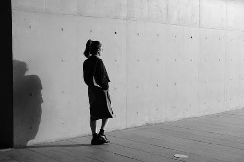 女人走在墙附近的灰度照片 · 免费素材图片
