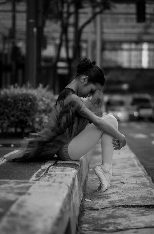 芭蕾舞女演员坐在大街上的黑白照片 · 免费素材图片