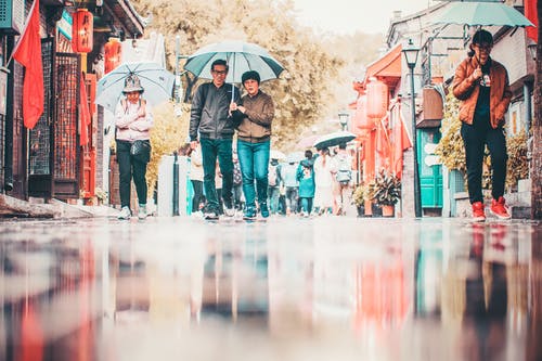 在大街上拿着雨伞走的人 · 免费素材图片