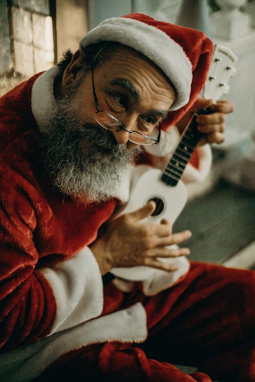 穿圣诞老人服装的人拿着白色尤克里里琴 · 免费素材图片