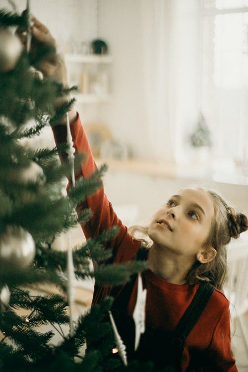 女孩到达一棵圣诞树的顶部 · 免费素材图片