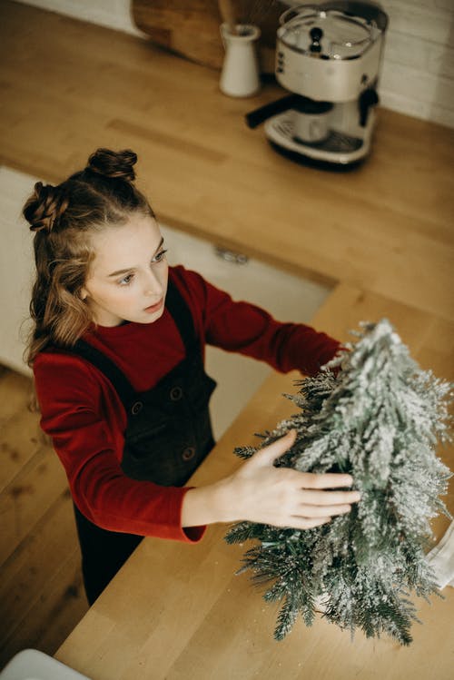 把圣诞树装饰放在柜台上的女孩 · 免费素材图片
