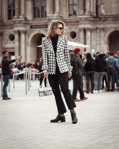 女人穿着黑色和白色格仔的西装外套站路面 · 免费素材图片