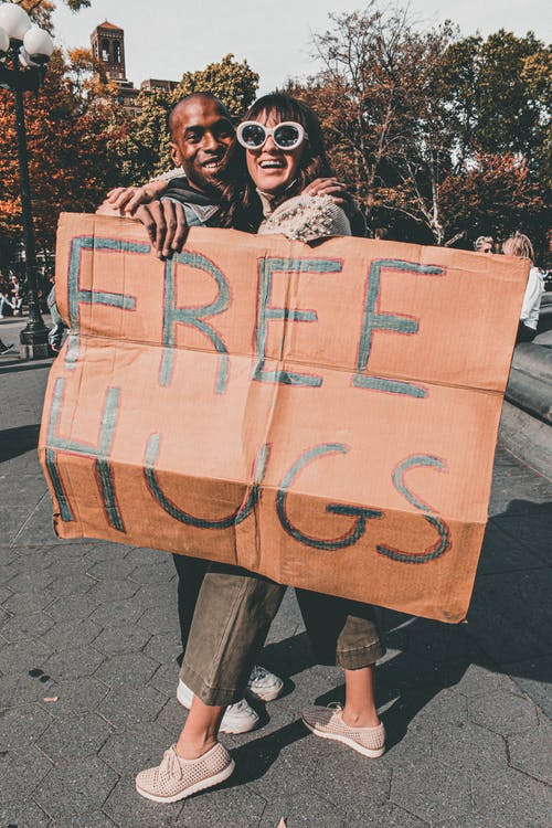 男人和女人抱着免费拥抱标牌 · 免费素材图片
