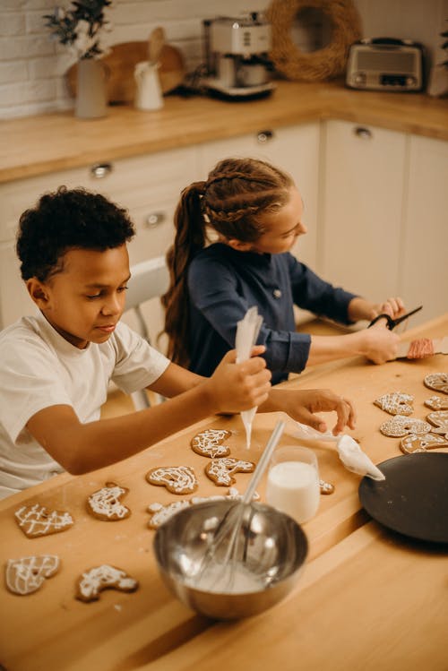 两个孩子在饼干上放奶油 · 免费素材图片