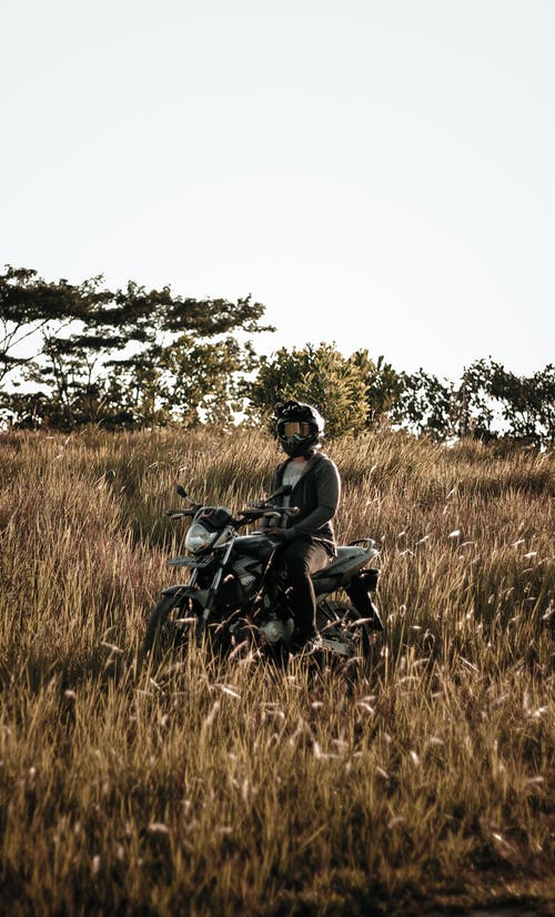 在草地上骑黑色摩托车的人 · 免费素材图片