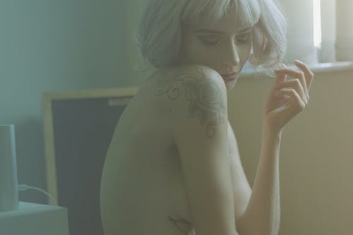 在她的肩膀和侧面上有纹身的裸体金发女人的特写 · 免费素材图片