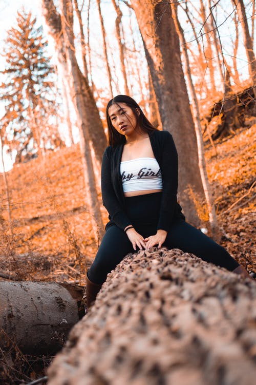 坐在倒下的树干上的黑色羊毛衫的女人的选择性聚焦摄影 · 免费素材图片