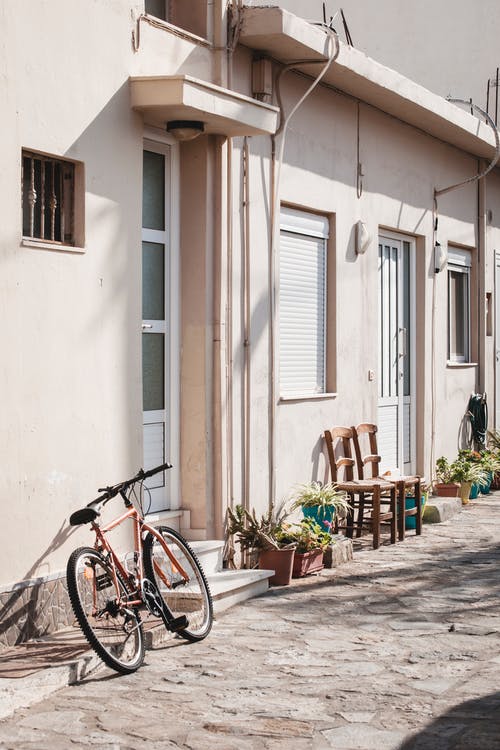 黑城市自行车停在白色混凝土建筑旁边 · 免费素材图片