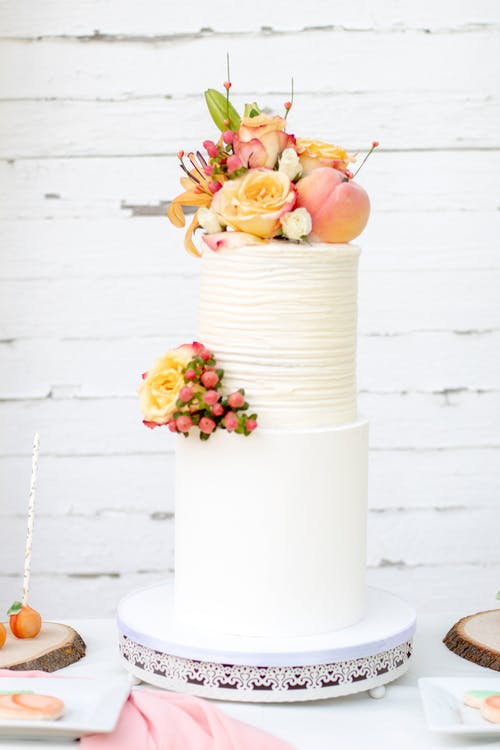 两层蛋糕上的黄色和粉红色花朵的浅焦点照片 · 免费素材图片