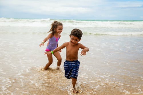 孩子们在海边跑步时微笑的照片 · 免费素材图片