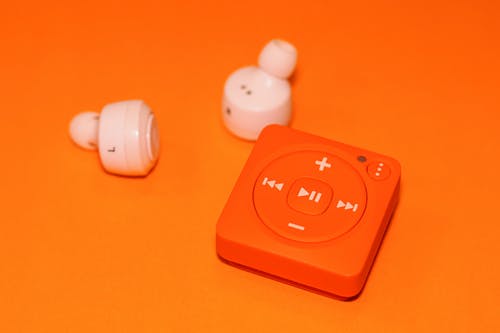 橙色音乐播放器旁边的白色耳机 · 免费素材图片