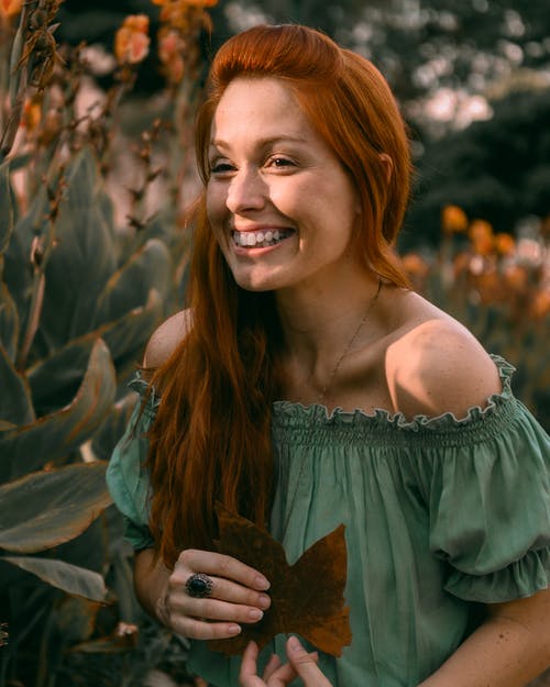 微笑的女士拿着叶子 · 免费素材图片