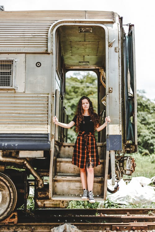 站在一列火车的门口的黑色和棕色格仔连衣裙的女人 · 免费素材图片