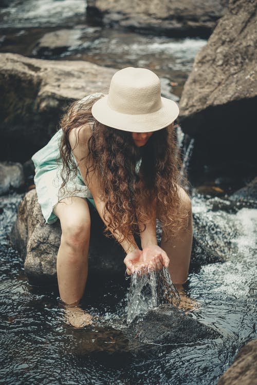 女人坐在岩石举行水 · 免费素材图片