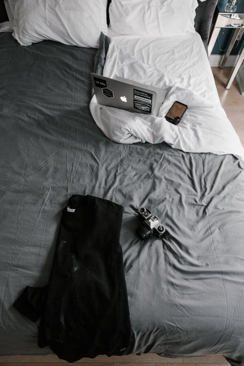 相机在床上的黑夹克 · 免费素材图片