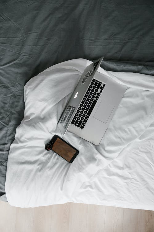 白色床上毯子上的银色macbook Pro · 免费素材图片