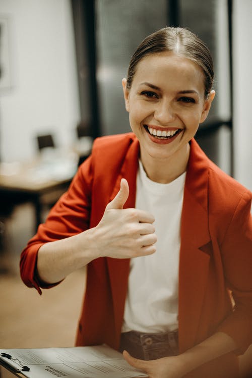 女人穿着橙色西装外套显示竖起大拇指 · 免费素材图片