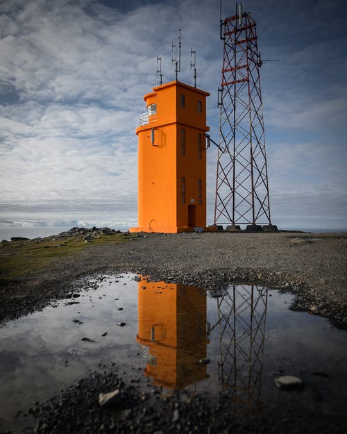 白天在金属塔旁边的橙色塔 · 免费素材图片