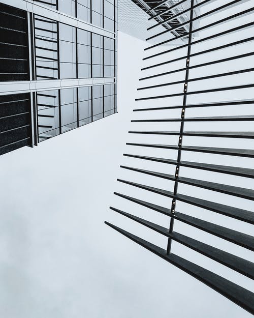 黑色和白色的现代建筑，与玻璃外观和铁栅栏的低角度拍摄 · 免费素材图片