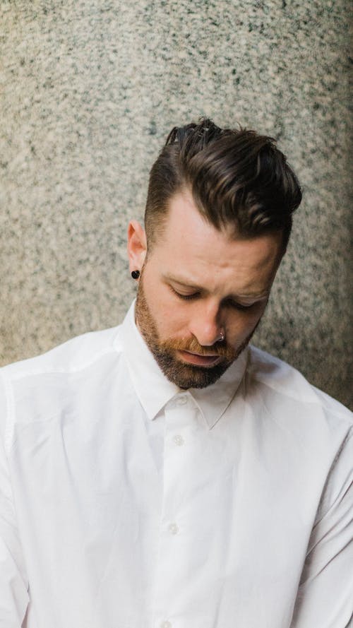 白色礼服衬衫的男人在往下看的墙旁边 · 免费素材图片