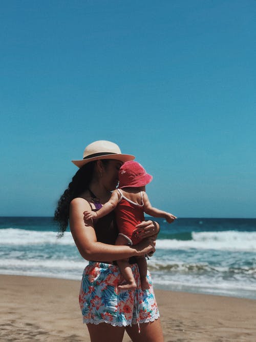 母亲在海滩上背着她的孩子 · 免费素材图片