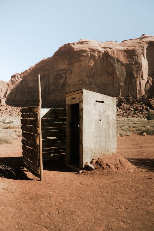 靠近沙漠岩石山建造的带有木栅栏的小型混凝土结构 · 免费素材图片