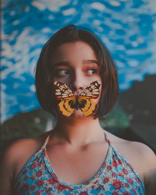 蝴蝶在嘴上的女人的照片 · 免费素材图片