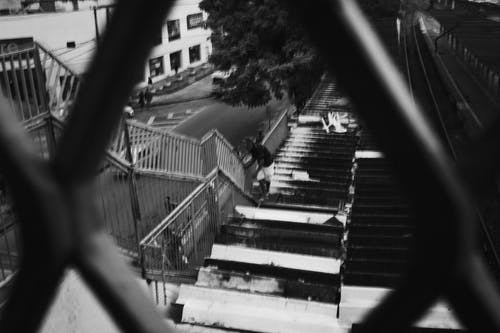 一个人拿着高钢栅栏作为支持的屋顶上的黑白照片 · 免费素材图片