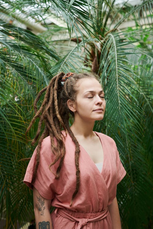 女人站在绿色的树叶附近时闭上眼睛的照片 · 免费素材图片