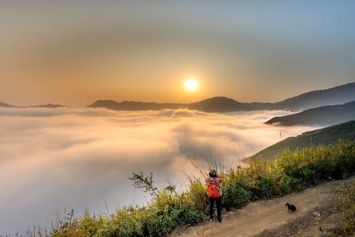 穿红色背包的人面对云海 · 免费素材图片