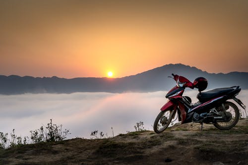 云海包围的山崖上的红色和黑色下层摩托车 · 免费素材图片