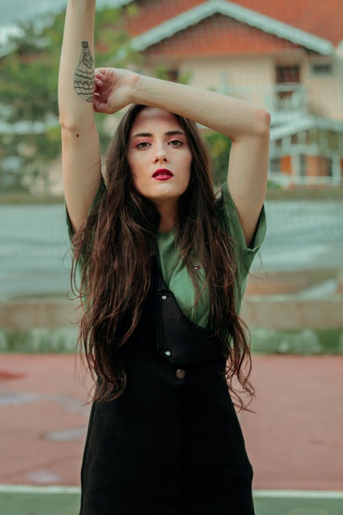 女人穿着黑色连衣裙与右手举起 · 免费素材图片