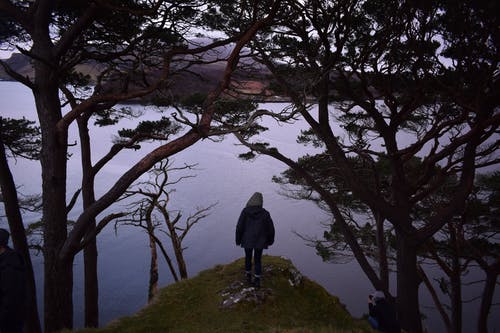 女人站在平静的水体附近 · 免费素材图片