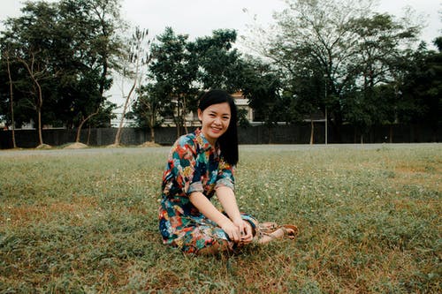 微笑的女士坐在草地上 · 免费素材图片