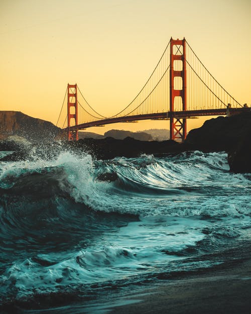 低角度拍摄的大浪在金门大桥下的海岸上崩溃 · 免费素材图片