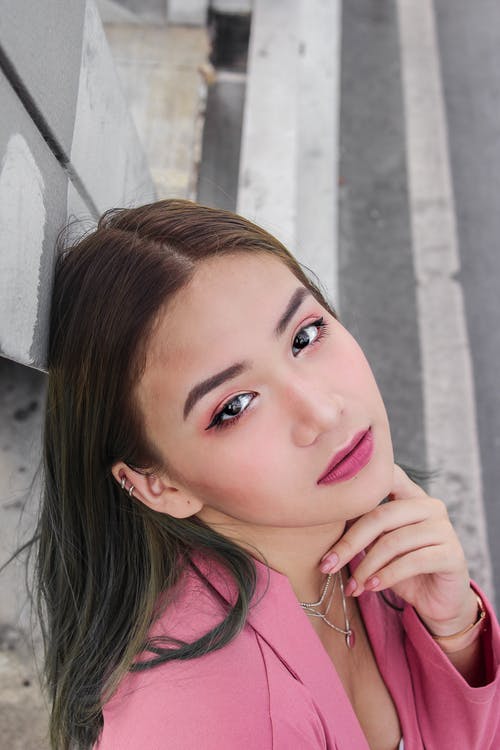 倚在墙上的粉红色上衣的女人 · 免费素材图片