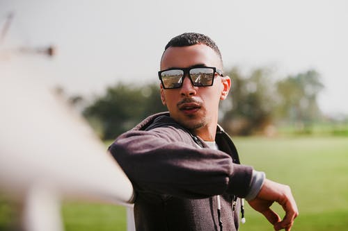 穿黑夹克的男人，戴着墨镜倚在白色的栏杆 · 免费素材图片