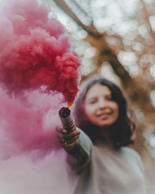 女人抱着粉红色的彩色烟雾弹 · 免费素材图片