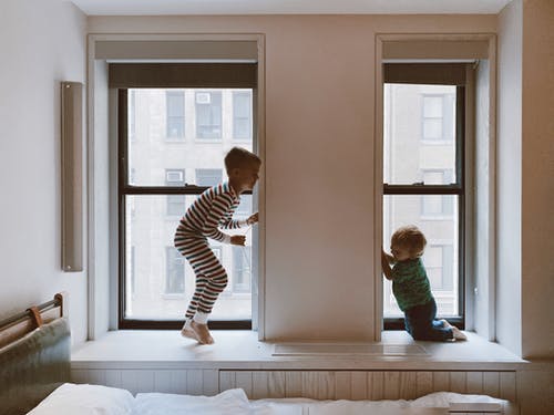 两个孩子在玻璃窗户旁边玩 · 免费素材图片