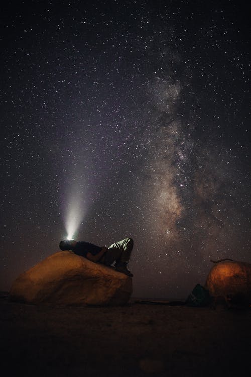 男子躺在石头凝视着银河系 · 免费素材图片