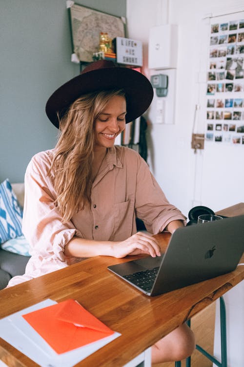 微笑的女士使用的便携式计算机 · 免费素材图片