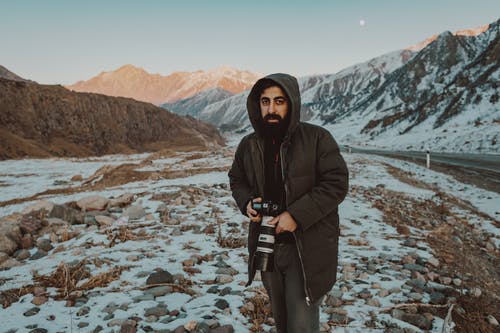 男子手持黑色单反相机 · 免费素材图片