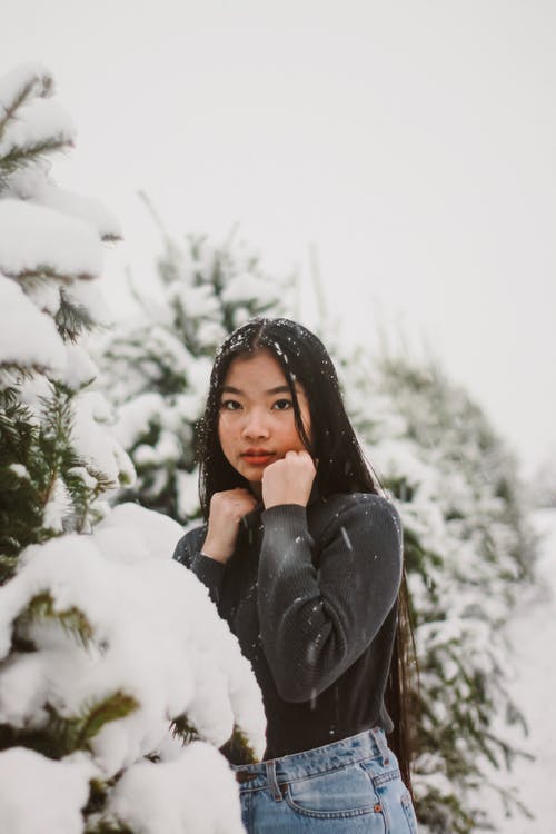 女人站在冰雪覆盖的树木旁边的选择性焦点摄影 · 免费素材图片