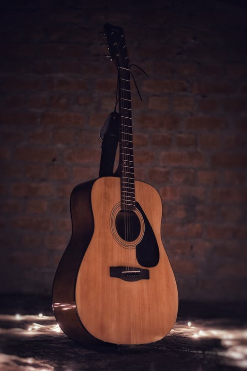 棕色砖墙上的原声吉他 · 免费素材图片